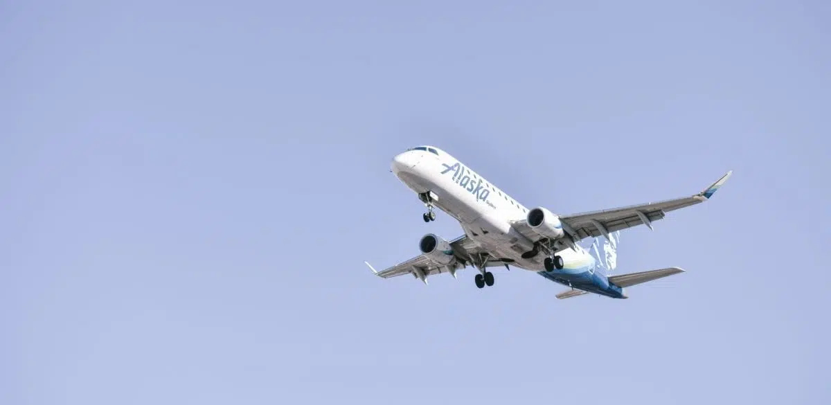 A large alaska passenger jet flying through a blue sky