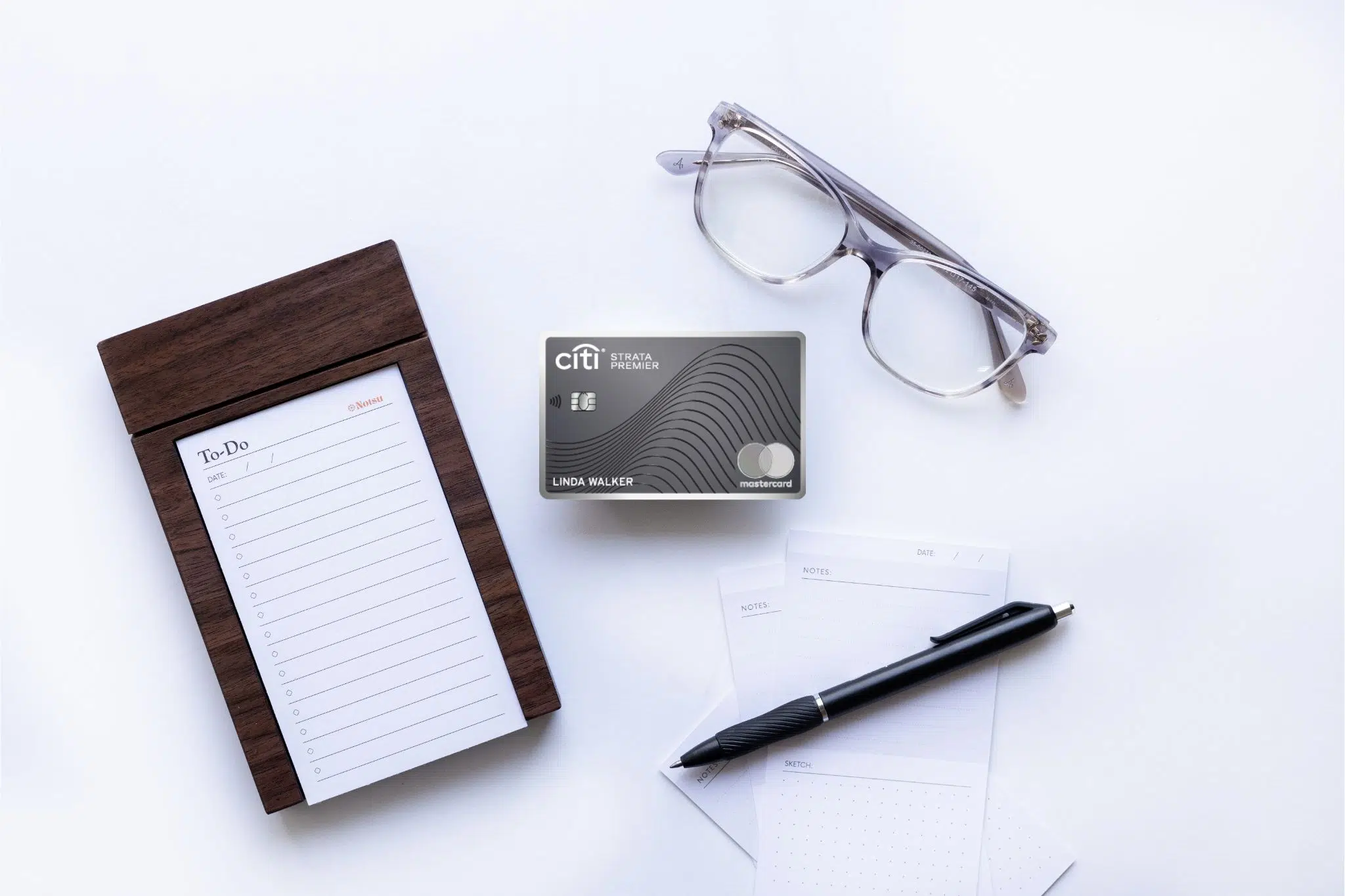 Citi Strata Premier card with glasses, notepad, and pen