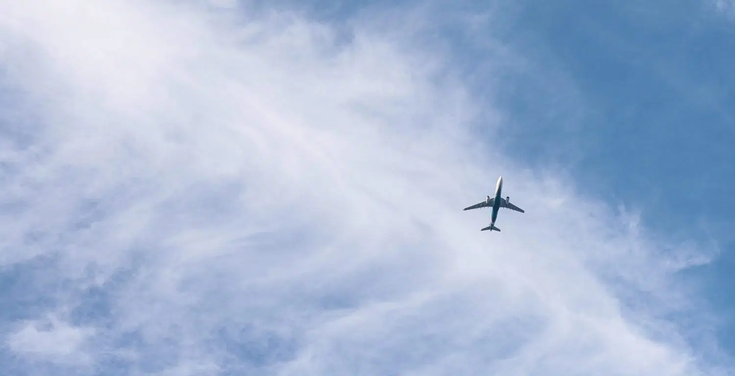 A large airplane flying high up in the air on a cloudy day