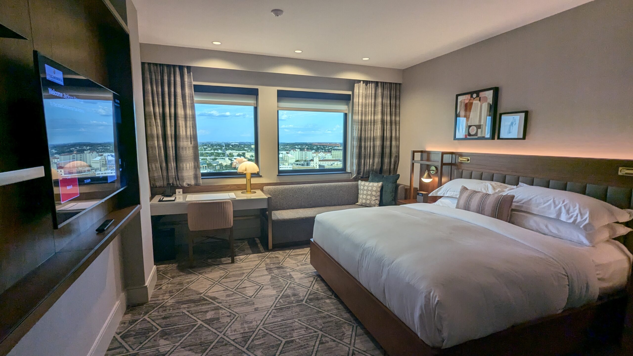 hotel room with a TV, desk, and king-sized bed