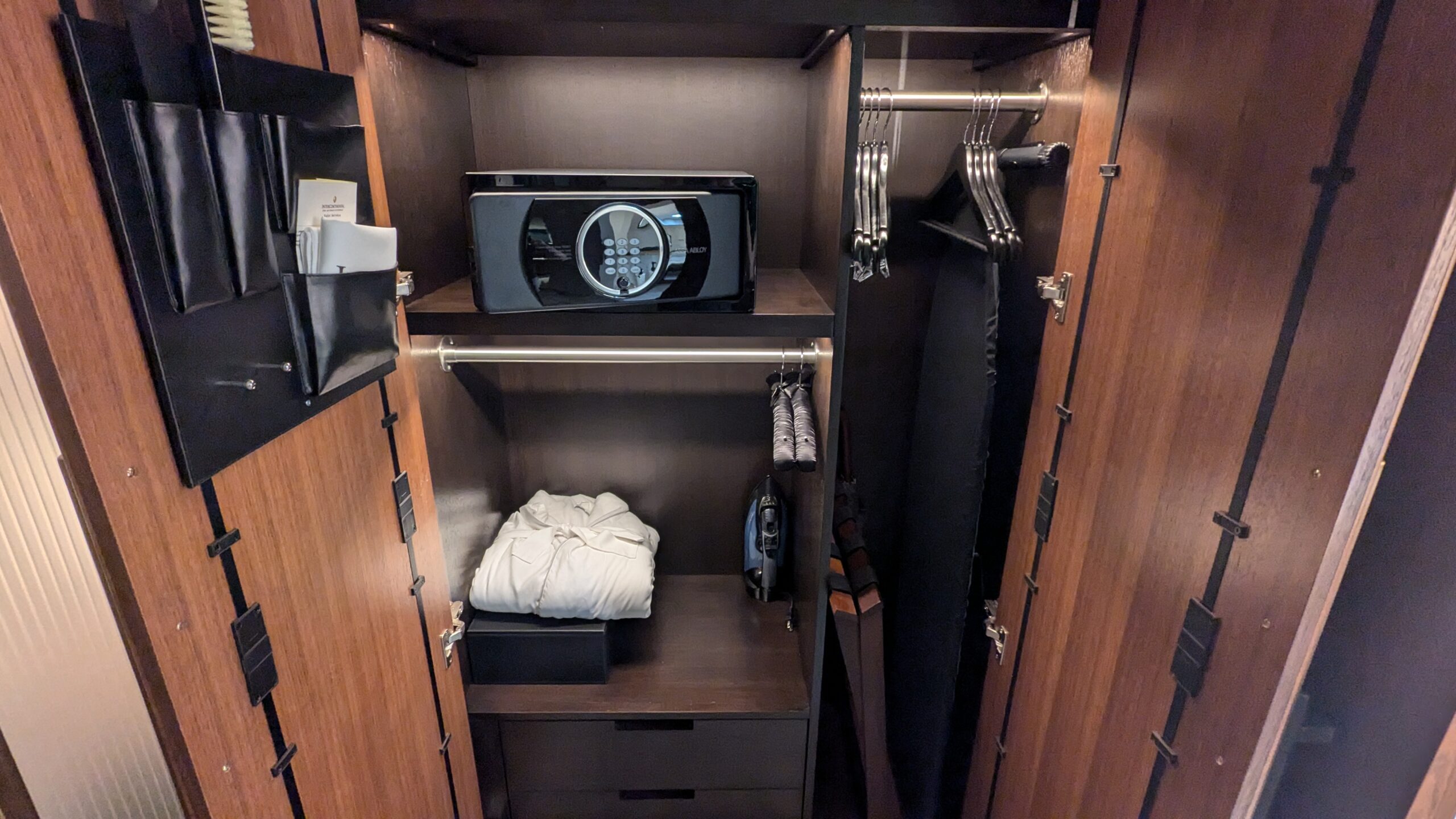 Inside of a wardrobe with safe, bath robe, and hangers. 