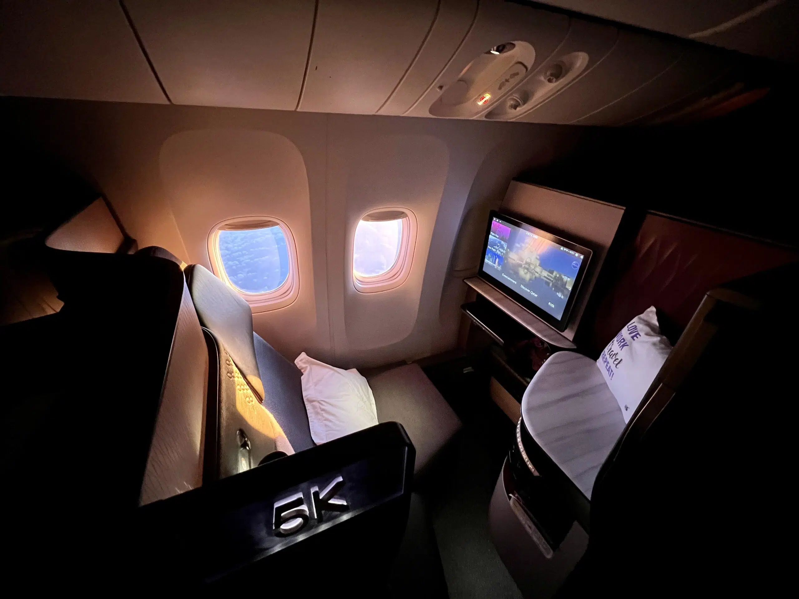 Qatar Airways Qsuite with the sun shining through two open airplane windows. 